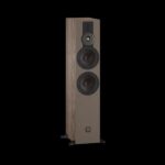 Tall floor-standing speaker with a wood veneer cabinet, featuring two large woofers, a midrange driver, a tweeter, and a small logo on the lower front panel against a black background.