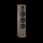 Tall floor-standing loudspeaker with four drivers (tweeter and three woofers) in wood veneer on a beige front, set against black background.